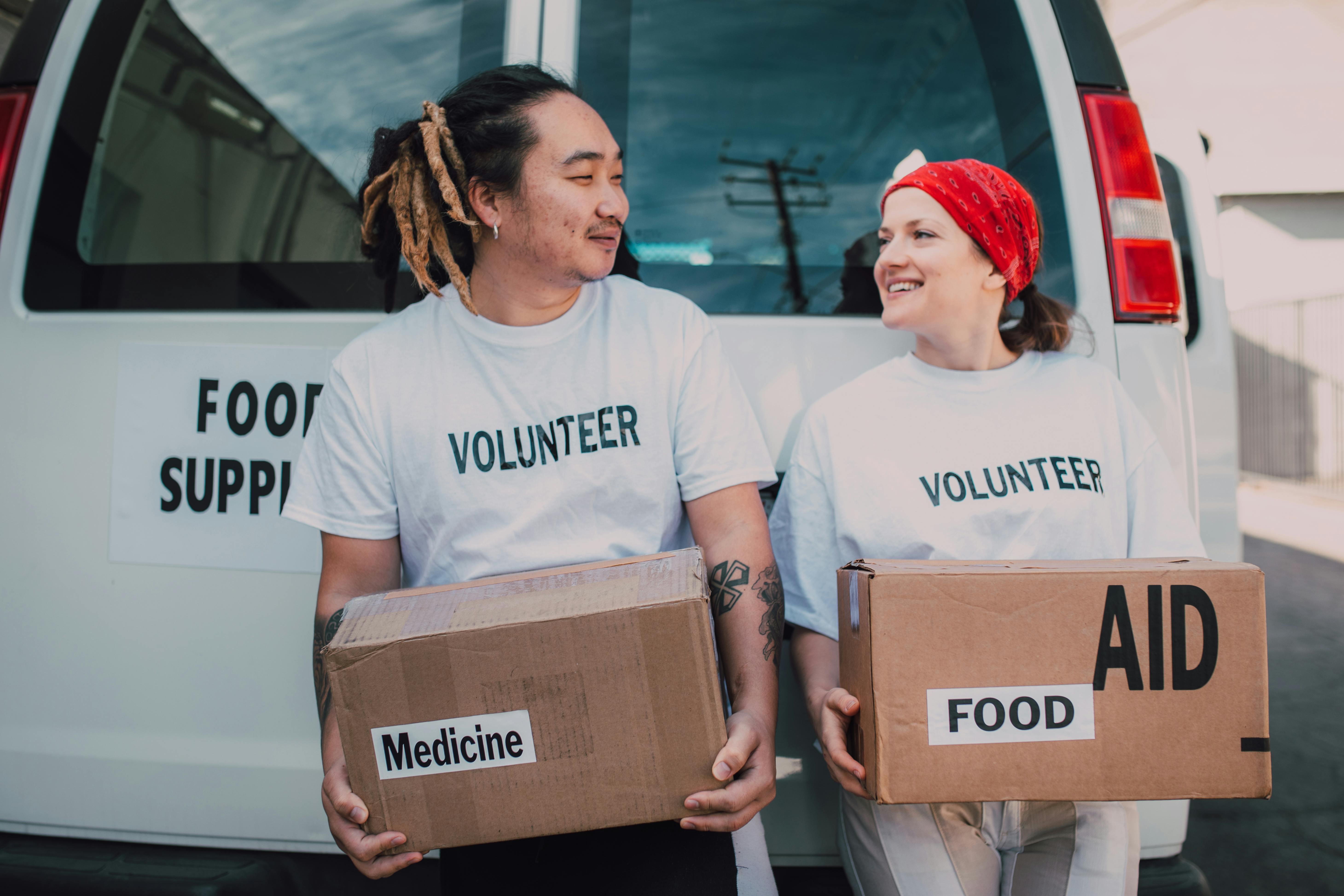 Two volunteers carrying boxes of food and medicine